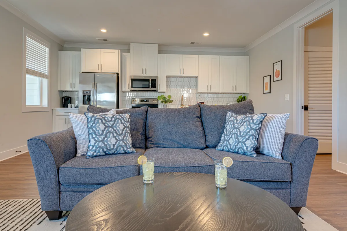 A perspective capturing both the cozy sofa and the kitchen area in the background, highlighting the open flow between lounging and entertaining spaces. The design encourages seamless movement and shared experiences, making it ideal for group stays and urban adventures.