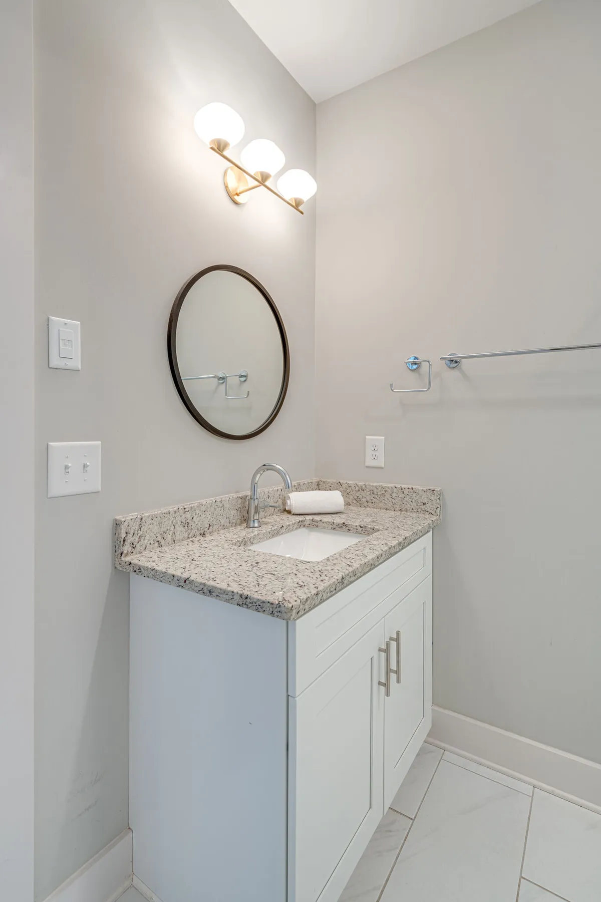 An inviting interior with a granite countertop, round mirror, and modern light fixture, setting the stage for guests to prepare for their night out or relax after an exciting event. The space is clean and stylish, suggesting comfort and readiness for gatherings.